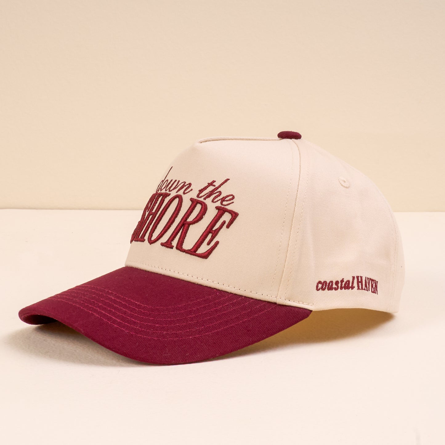 Cap with 'Down the Shore' and 'coastal HAVEN' text on a beige background