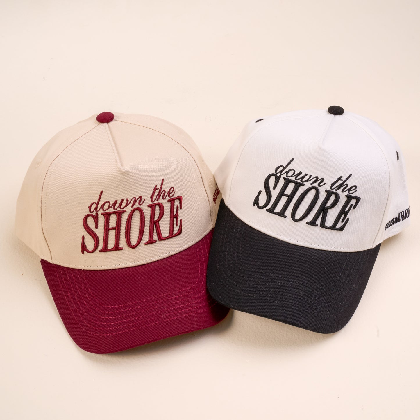 Two baseball caps with 'down the Shore' text on a beige background